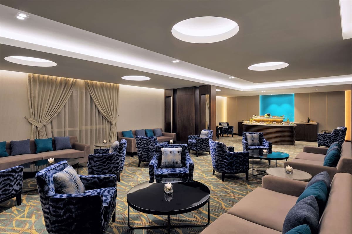 A hotel lobby with a sofa, chairs, a coffee table, and a reception desk.