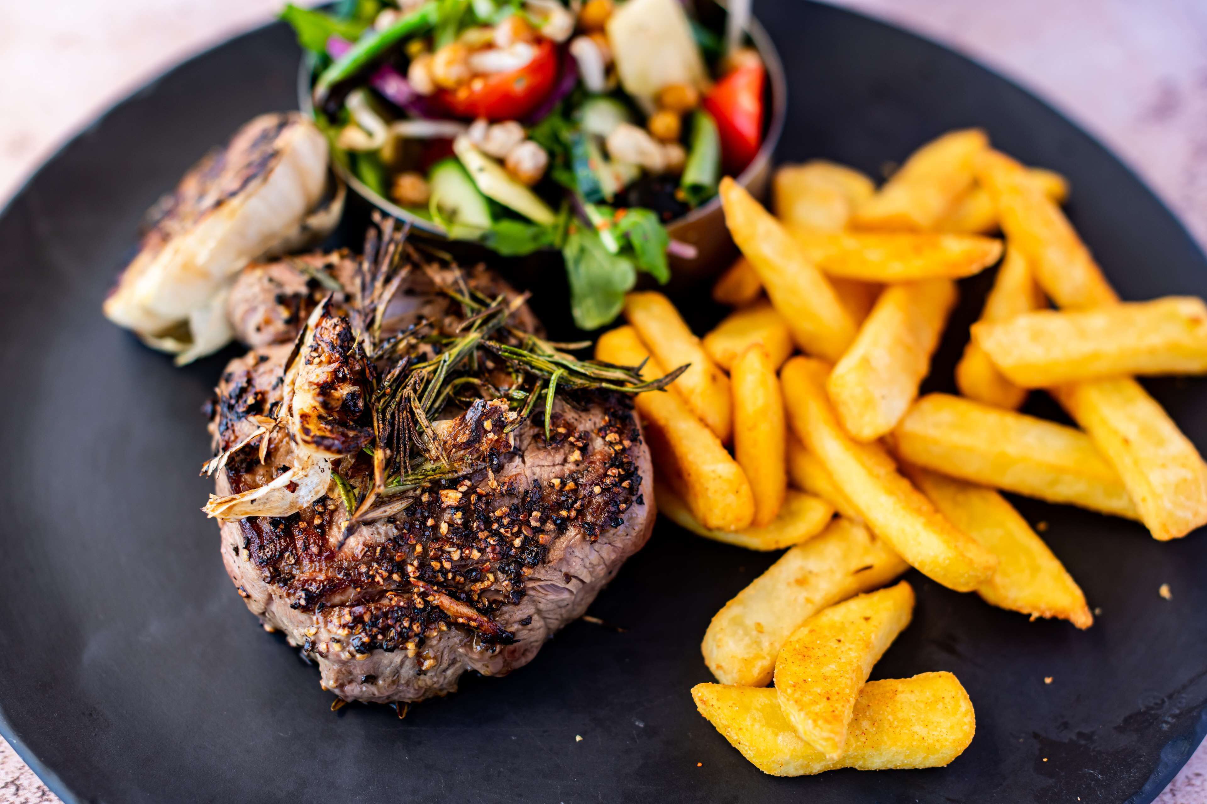A plate with grilled steak, fries, and a salad.
