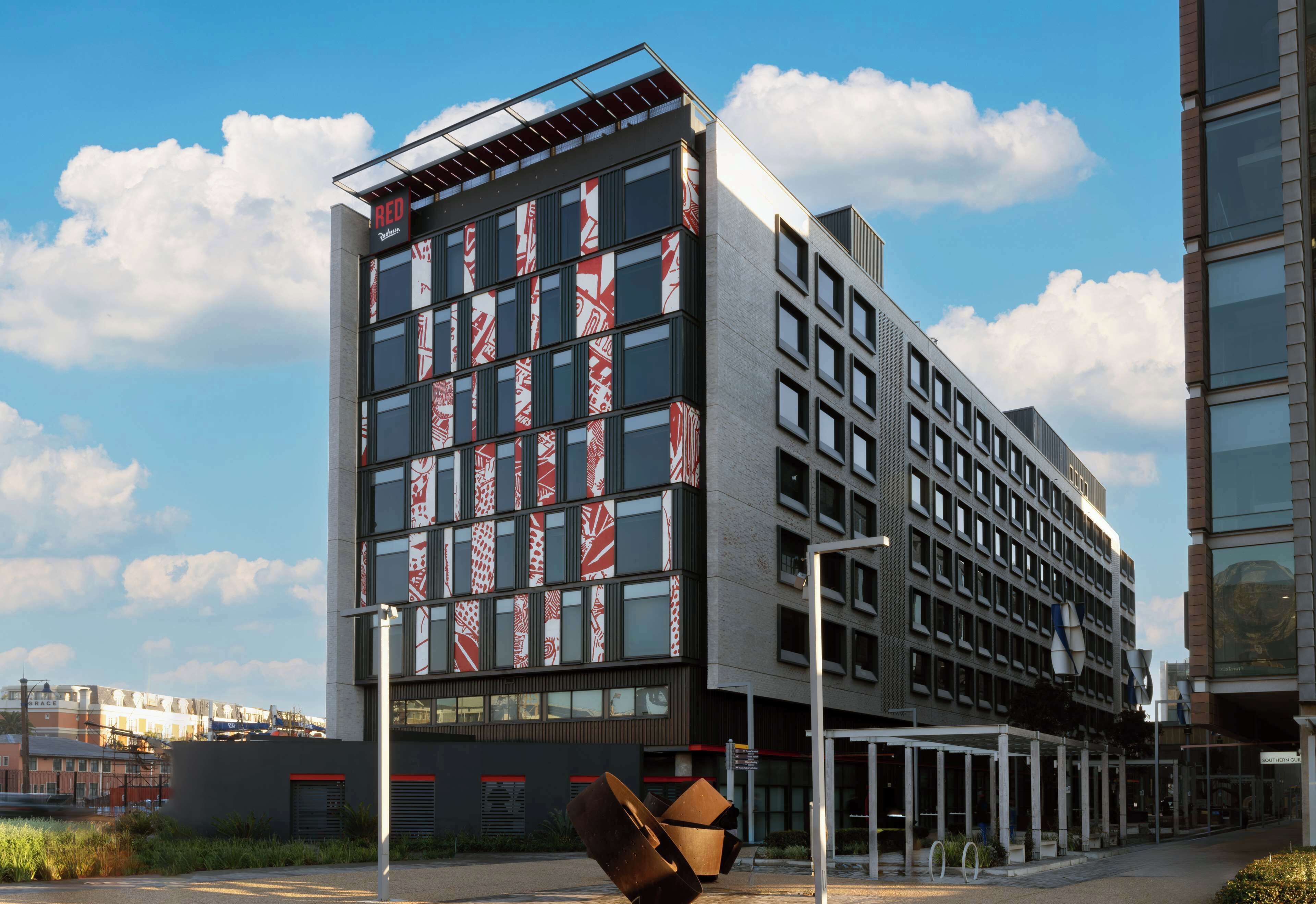 A modern building with multiple floors, large windows, and a prominent red sign.