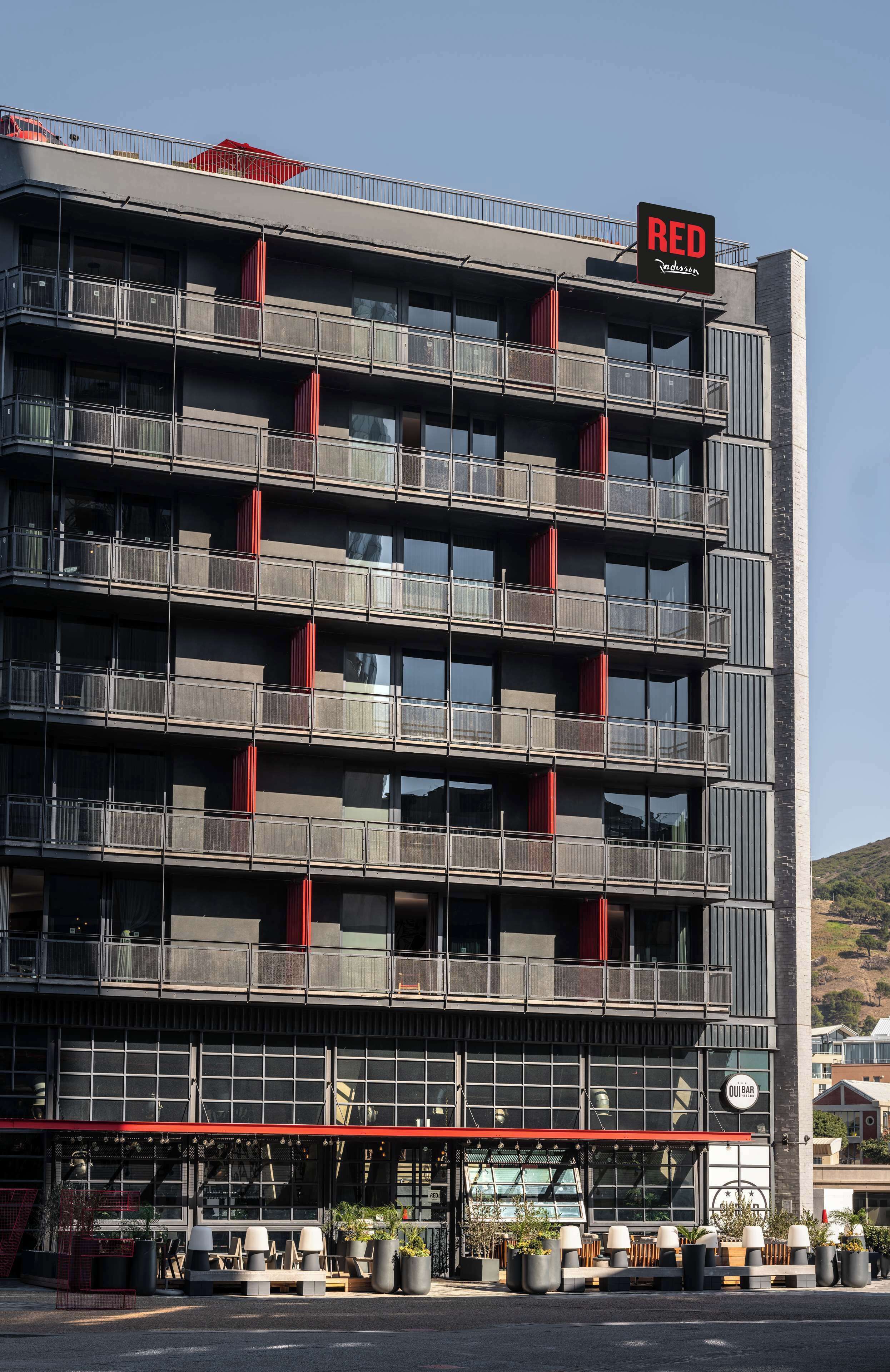 Un immeuble à plusieurs étages doté de balcons, d’une marquise rouge et d’une enseigne indiquant qu’il s’agit d’un restaurant.