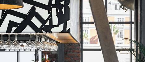 Un área de bar moderna con un grifo de cobre, copas colgantes y una mezcla de muebles de madera y metal.
