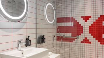 A modern bathroom with a white sink, two mirrors, and a red-tiled wall.