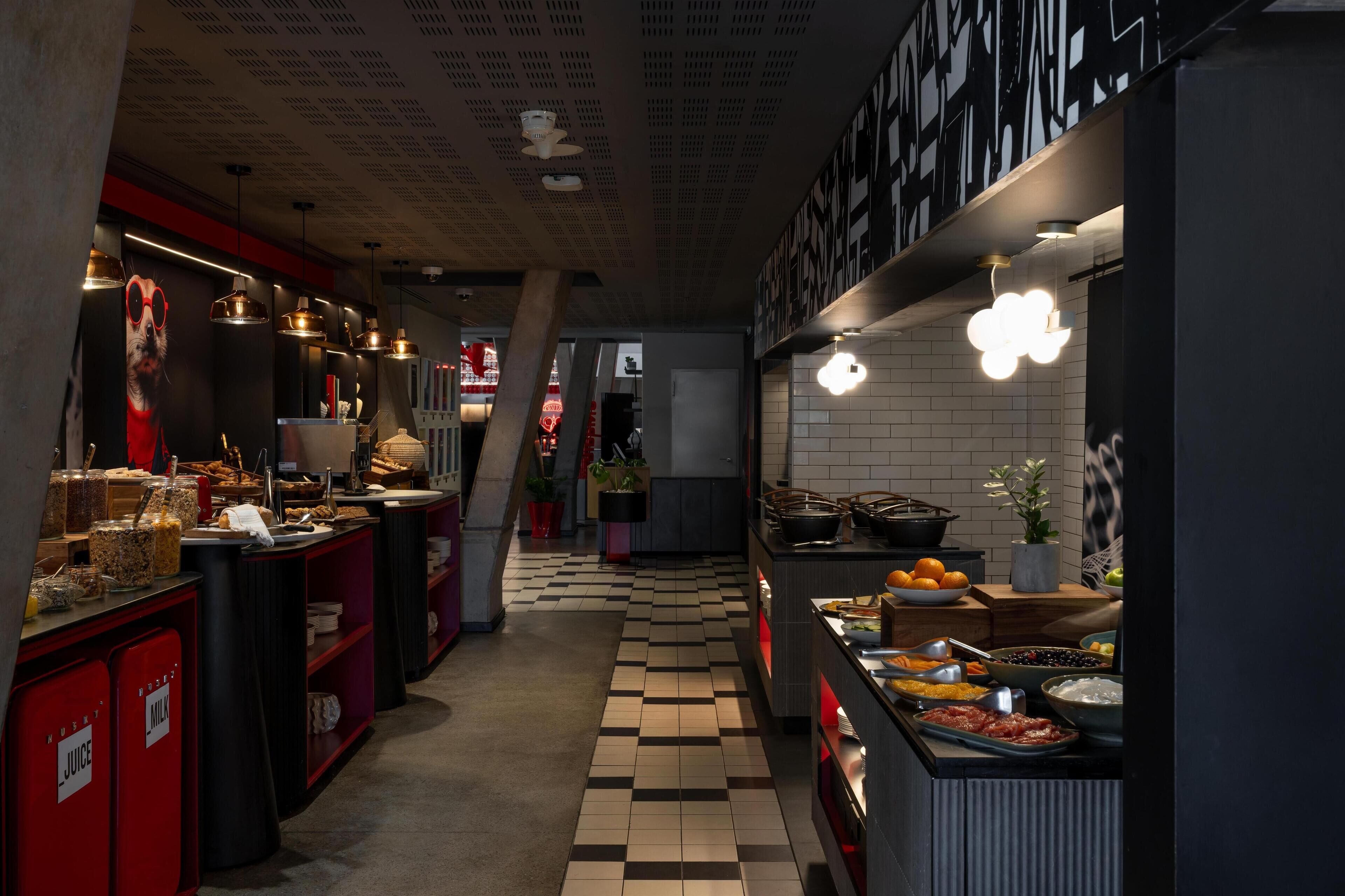 A modern kitchen with a checkered floor, various food stations, and hanging pendant lights.