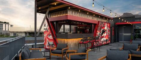 An outdoor seating area with wooden chairs and a bar with a red and black design.