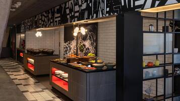 Une cuisine moderne avec un carrelage à motifs, un mur aux motifs noir et blanc, et une variété d’aliments exposés sur le comptoir.