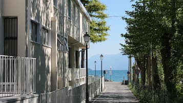 Ein Küstenweg mit einem Gebäude links, freiem Blick auf das Meer und Straßenlaternen entlang des Weges.