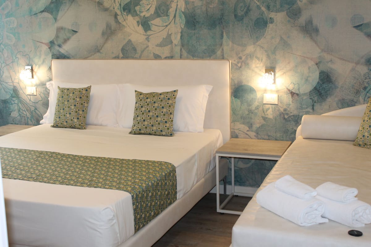 Ein Hotelzimmer mit einem großen Bett, zwei Kissen, einem Nachttisch und einer Wandleuchte.