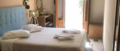 Un dormitorio con cama, una silla, un escritorio y un espejo.