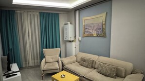 A living room with a sofa, armchair, coffee table, and a painting on the wall. - Kadikoy Arya Hotel (Istanbul)