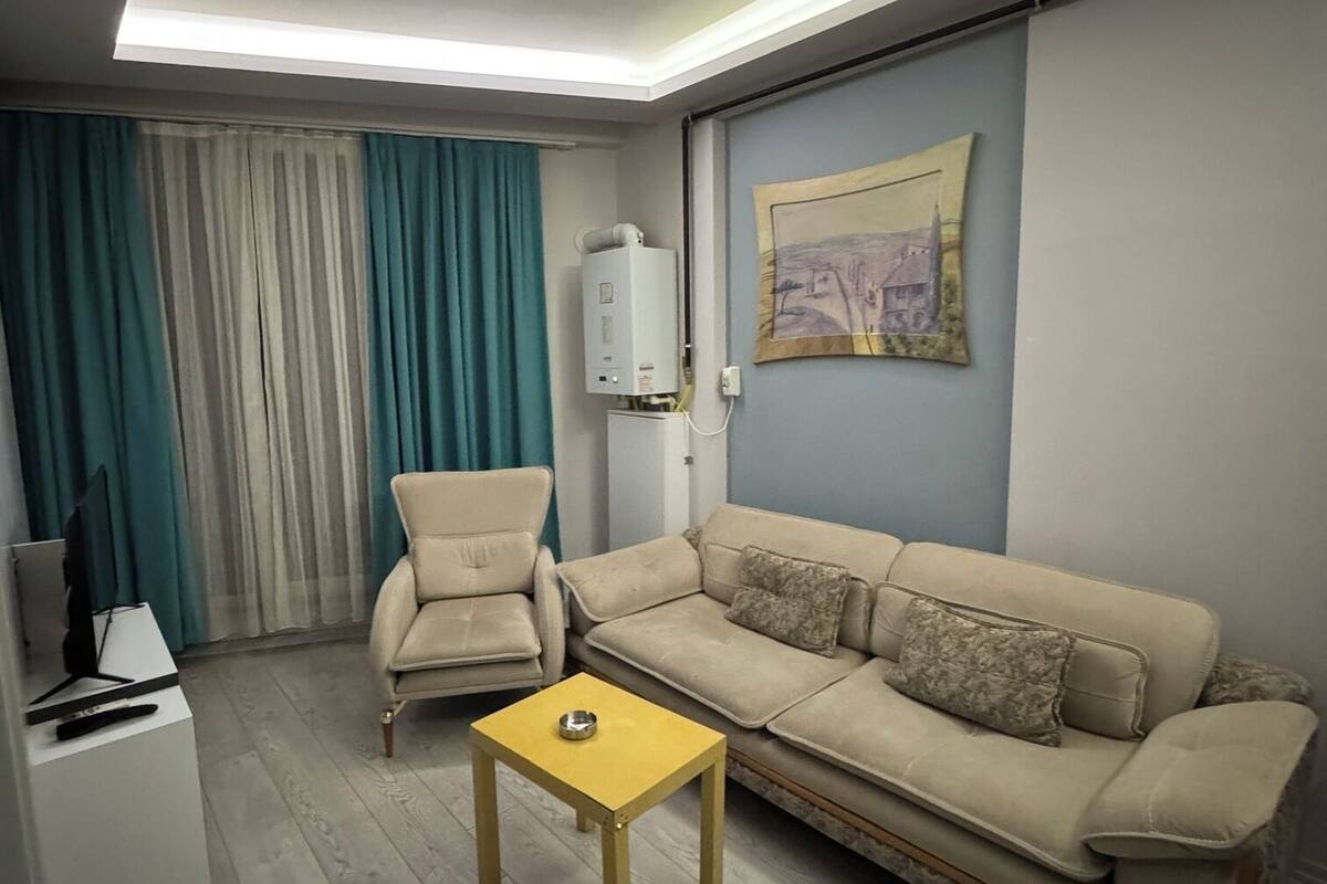 A living room with a sofa, armchair, coffee table, and a painting on the wall.