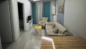 A modern living room with a sofa, a coffee table, and a TV. - Kadikoy Arya Hotel (Istanbul)