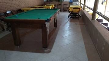 A pool table with a green felt surface, surrounded by chairs and tables.