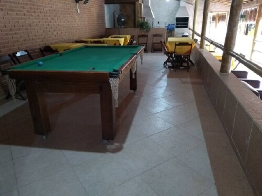 A pool table with a green felt surface, surrounded by chairs and tables.
