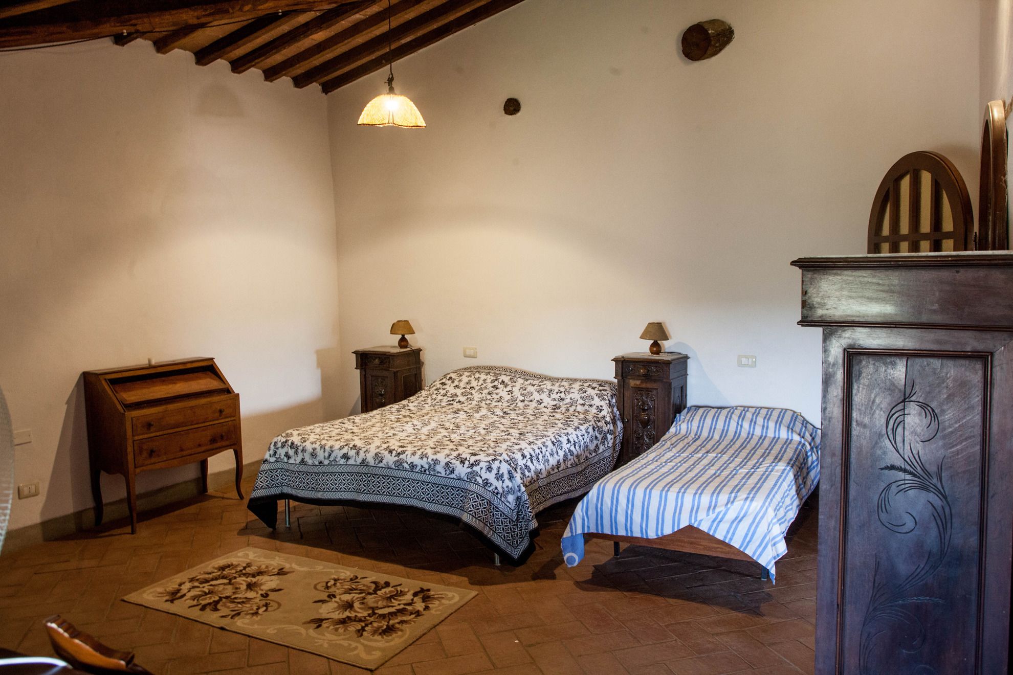 A bedroom with two beds, a wooden dresser, and a small table with lamps.