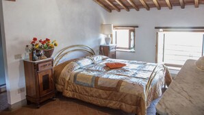 Un dormitorio con estructura de cama de madera, una mesita de noche con lámpara, una ventana con vistas y un ventanal con vistas.