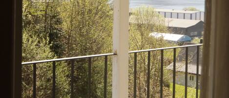 A balcony with a view of a lake and surrounding greenery.