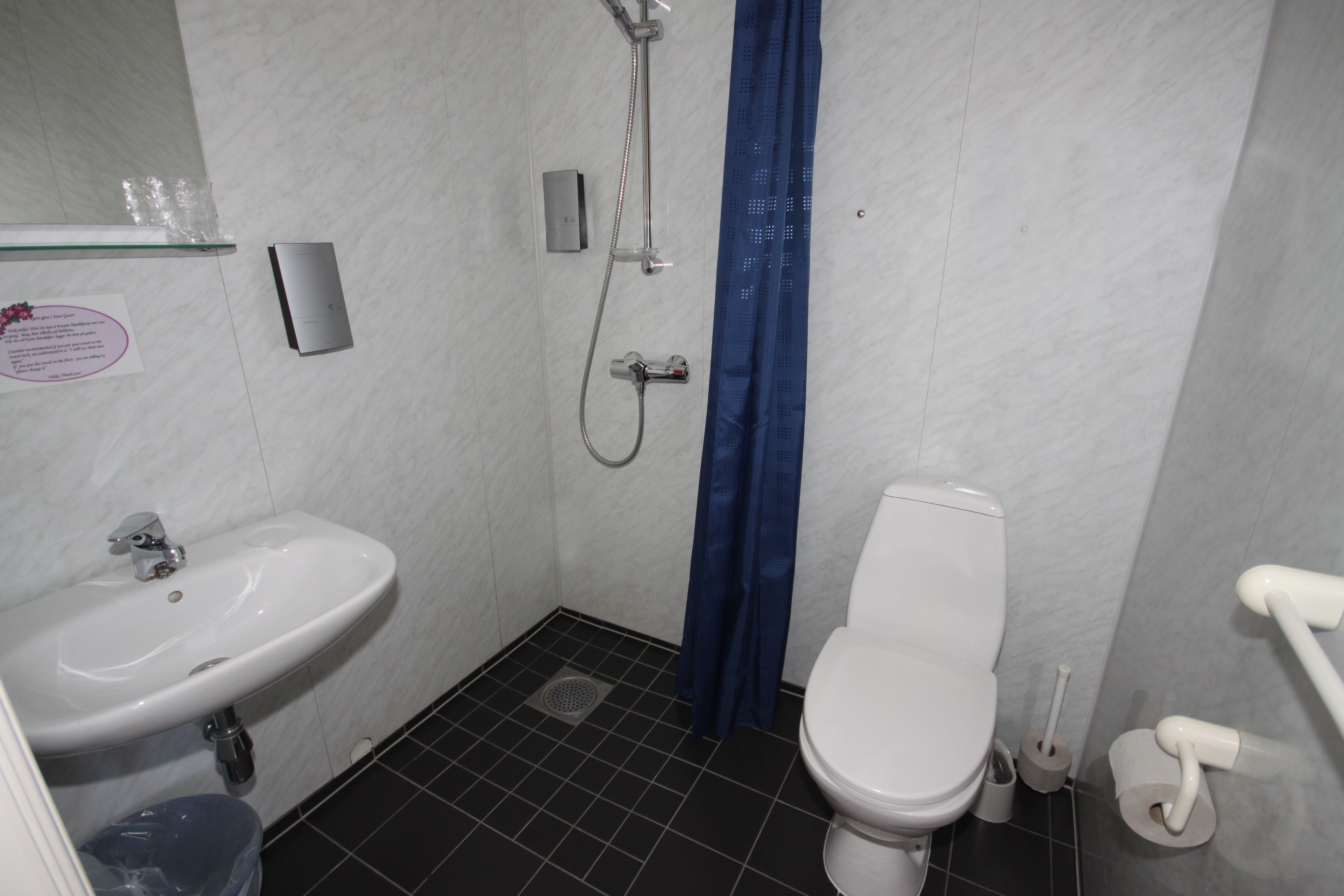 A small, clean bathroom with a white sink, toilet, and shower.