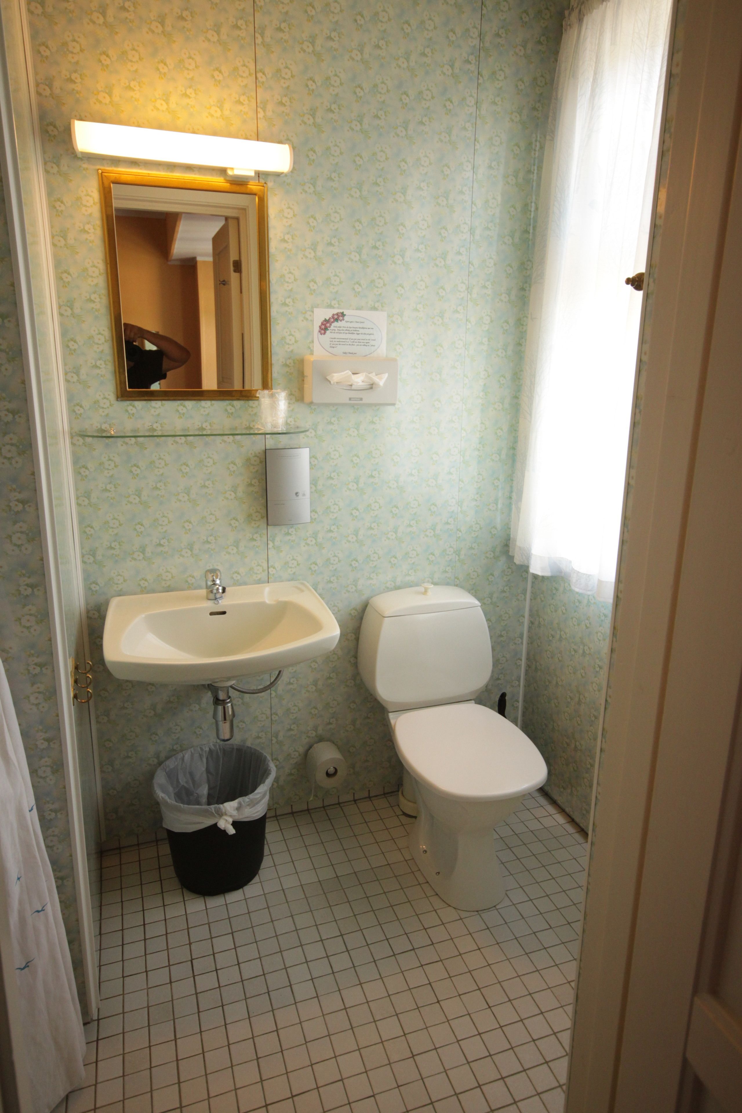 A bathroom with a sink, toilet, and a trash can.