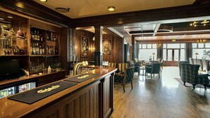 A bar area with wooden paneling, a bar counter, and a seating area with upholstered chairs and a table. - Sauda Fjordhotell (Sauda)