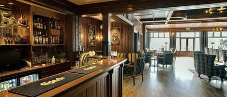 Eine Barbereich mit Holzwandverkleidung, einer Bar und einer Sitzecke mit gepolsterten Stühlen und einem Tisch.