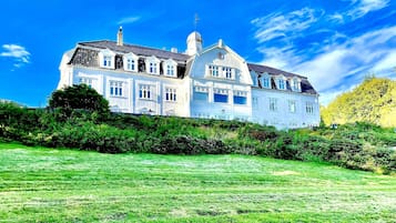 Situated on a lush green lawn, this stately building features a central tower and symmetrical facade with a series of windows.