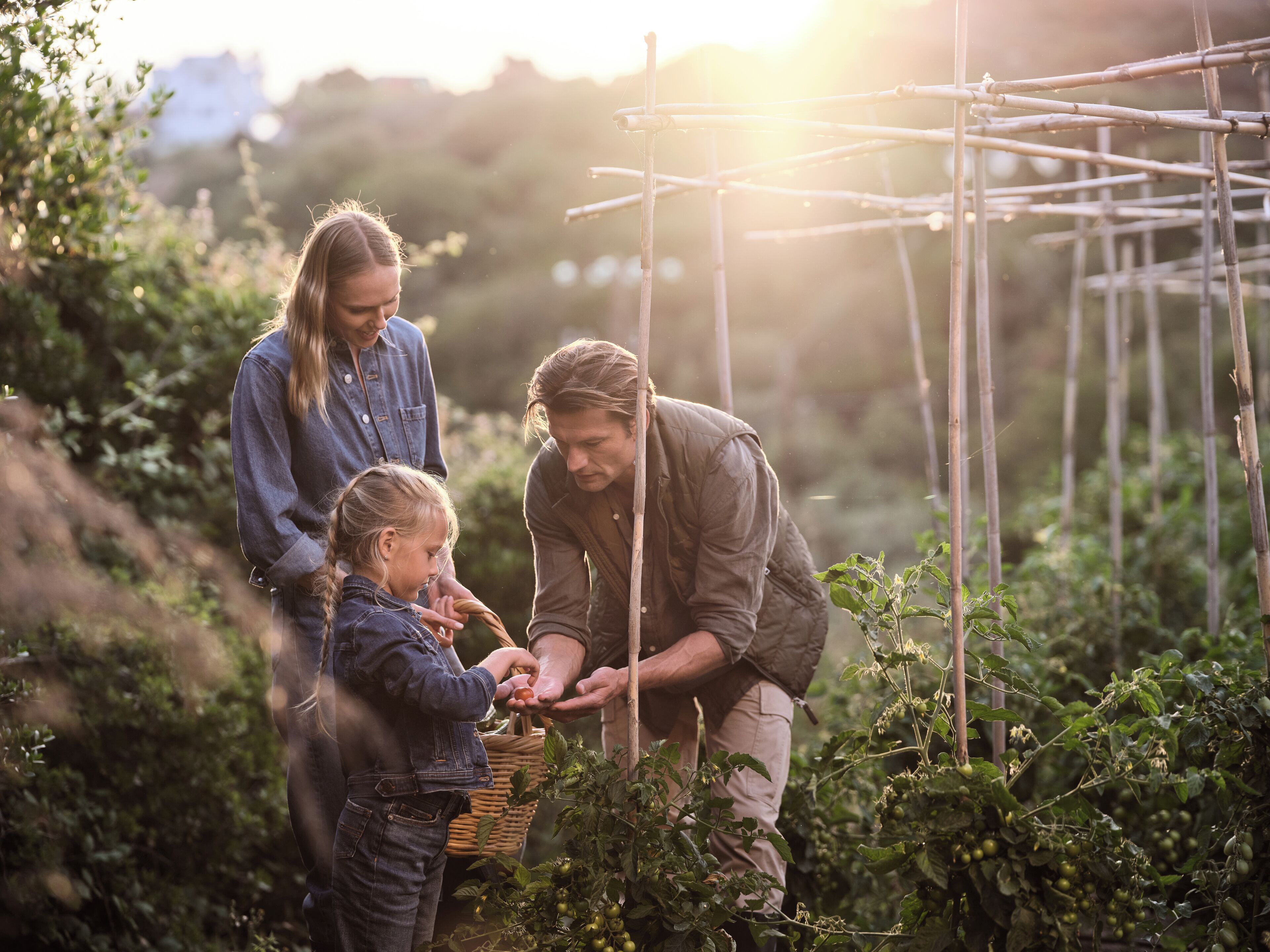 Una familia en un jardín con una estructura de enrejado y follaje.
