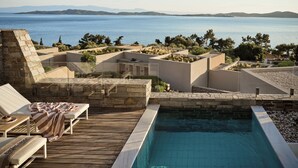 A pool area with a view of the sea, lounge chairs, and a stone wall. - Eagles Villas - Small Luxury Hotels of The World (Aristotelis)