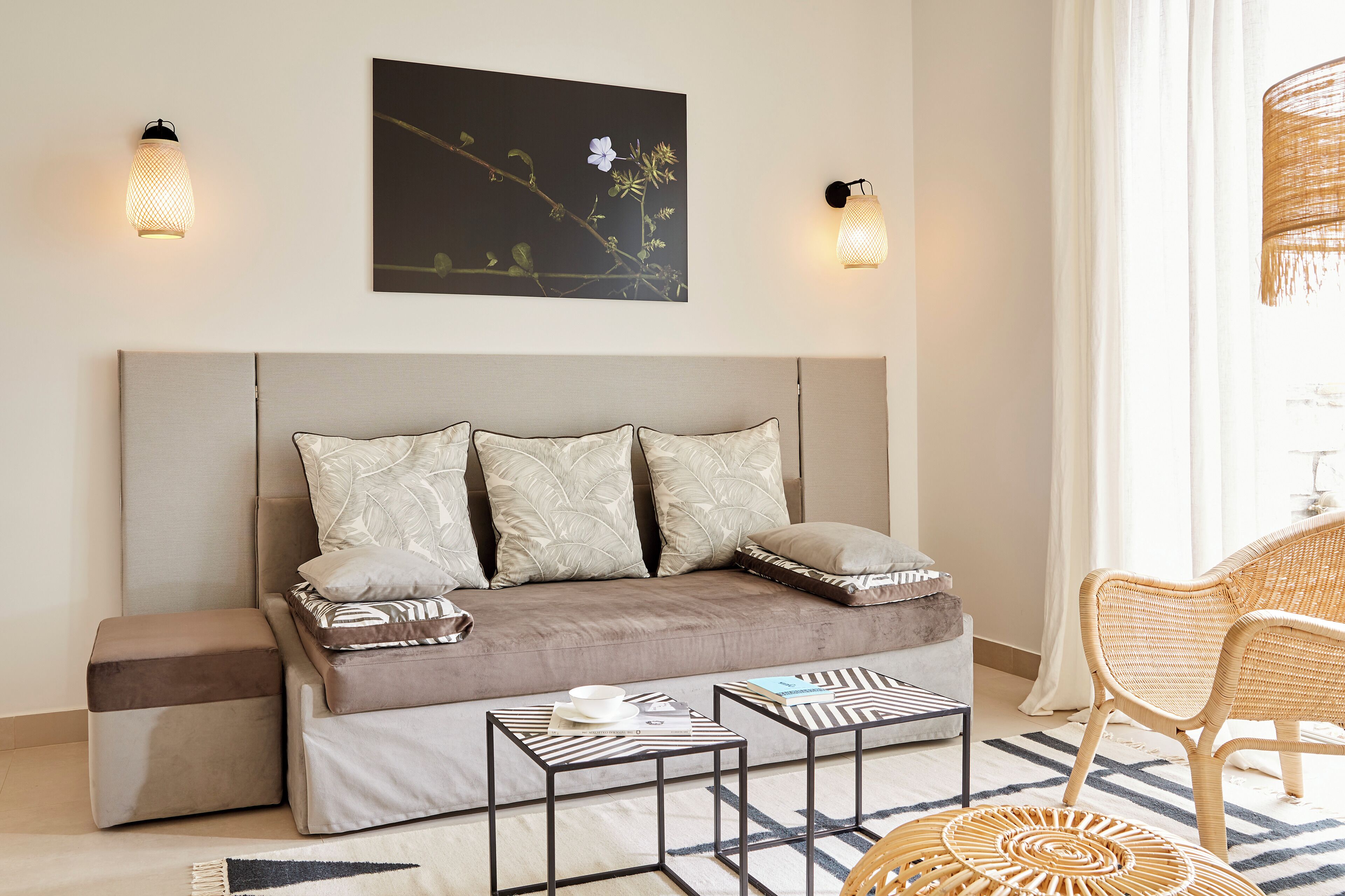 Ett modernt sovrum med en soffa, två sidobord, en stol och en tavla på väggen.