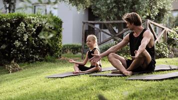 Deux personnes assises sur des tapis de yoga, à l’extérieur, sur l’herbe.