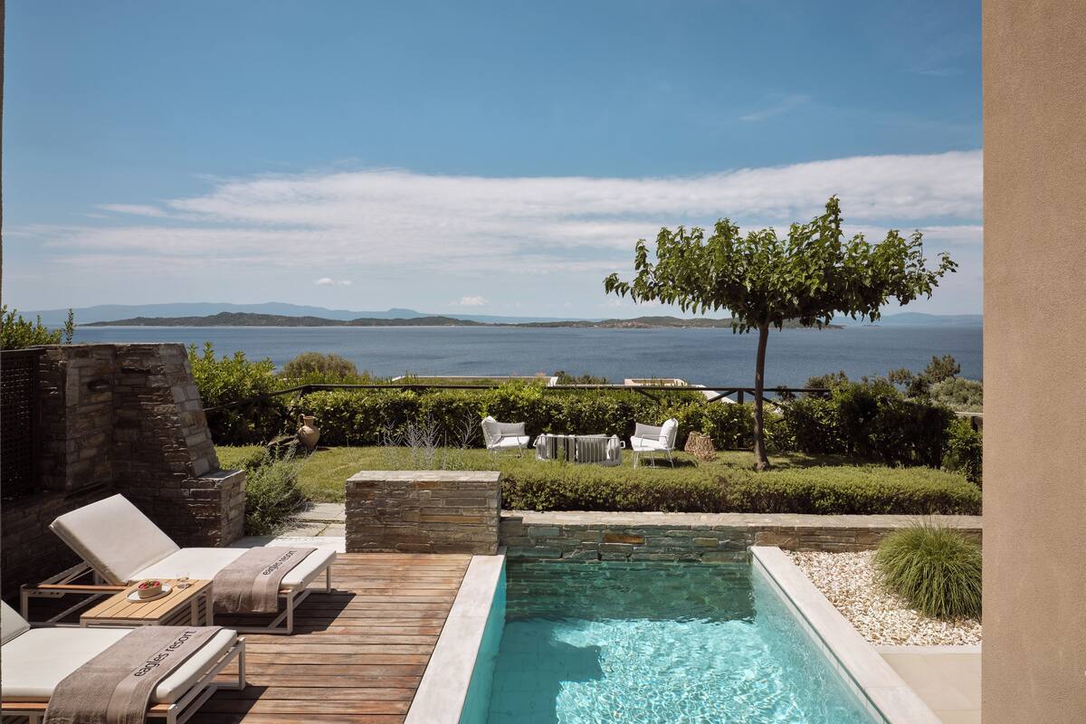 Ein Poolbereich mit Liegestühlen und Blick aufs Meer.