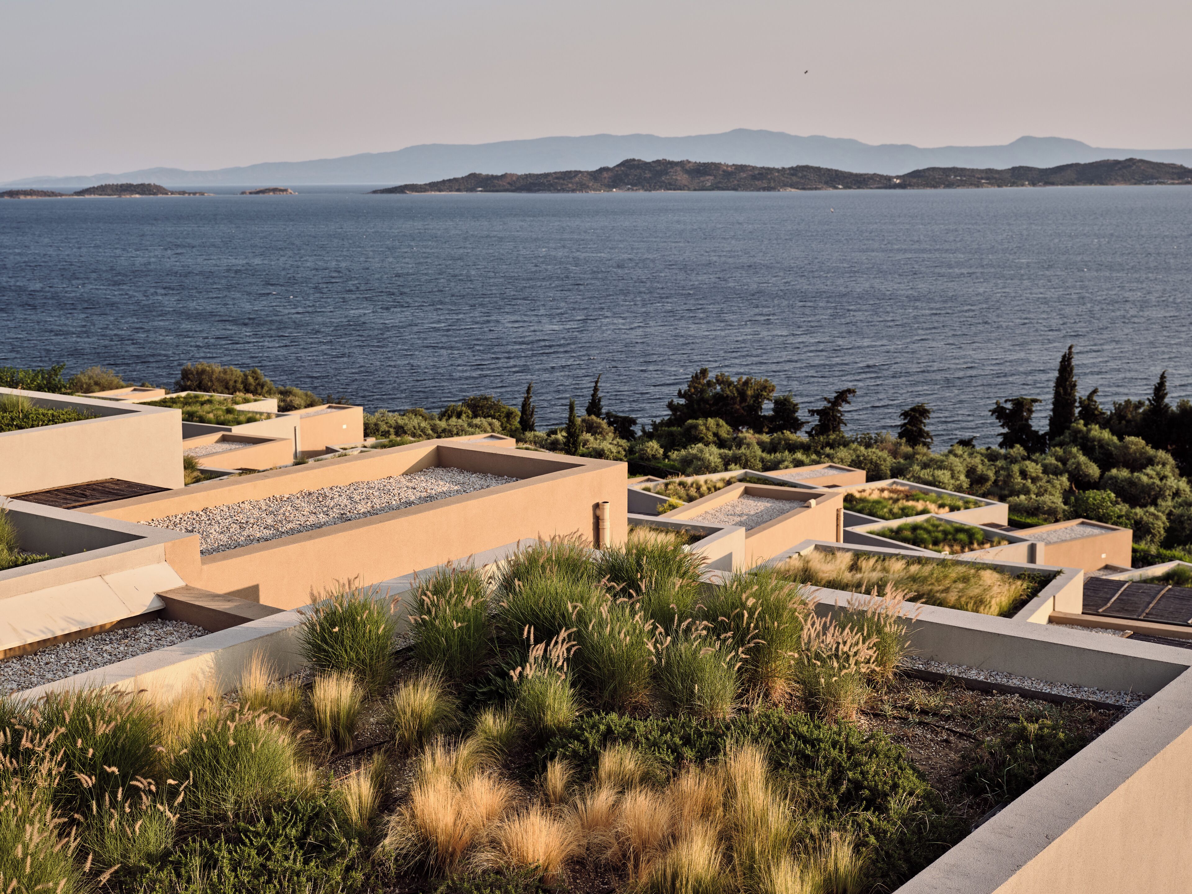 A coastal property with a rooftop garden and a view of the sea and distant mountains.