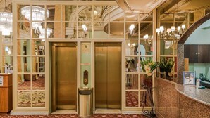 Un intérieur comprenant deux ascenseurs, un comptoir d’accueil et des lustres décoratifs.