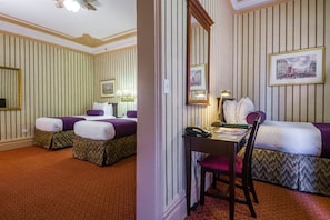 A hotel room with two beds, a desk, and a chair.