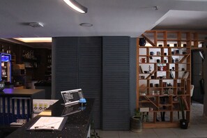 A modern interior with a bar area, a desk with a laptop, and a shelving unit with various items. - A Hotels & Suites  (Ankara)