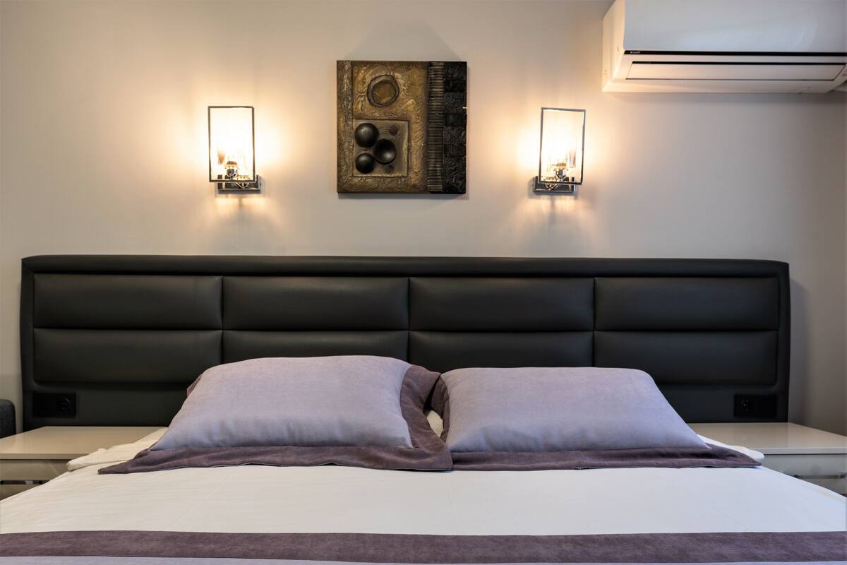 A hotel room with a large bed, two wall-mounted lights, and a decorative wall piece.