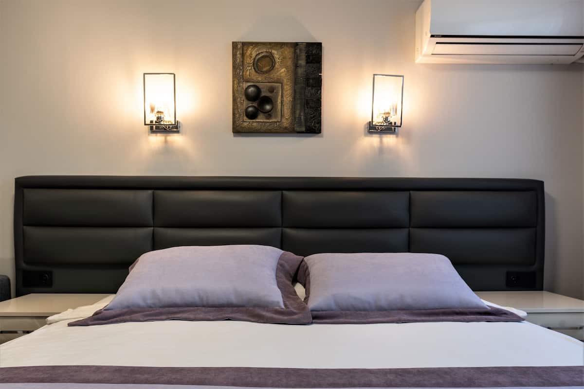A hotel room with a large bed, two wall-mounted lights, and a decorative wall piece.