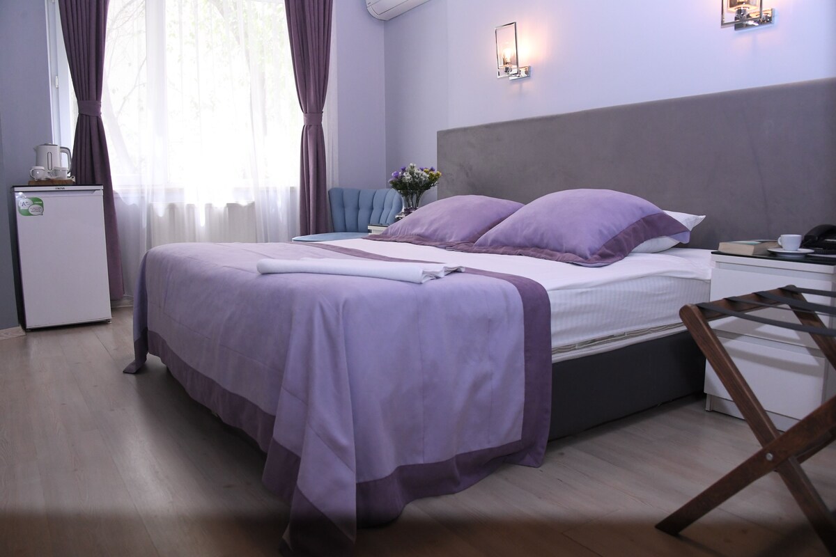 A neatly arranged bedroom with a bed, bedside table, and a small desk with a chair.