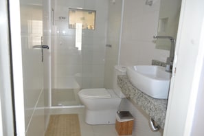Un baño con inodoro, lavamanos y cabina de ducha.