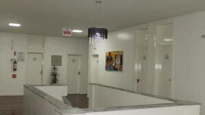 A hotel lobby with a reception desk, a staircase, and a fire extinguisher on the wall. - Sumare Hotel (Florianópolis)