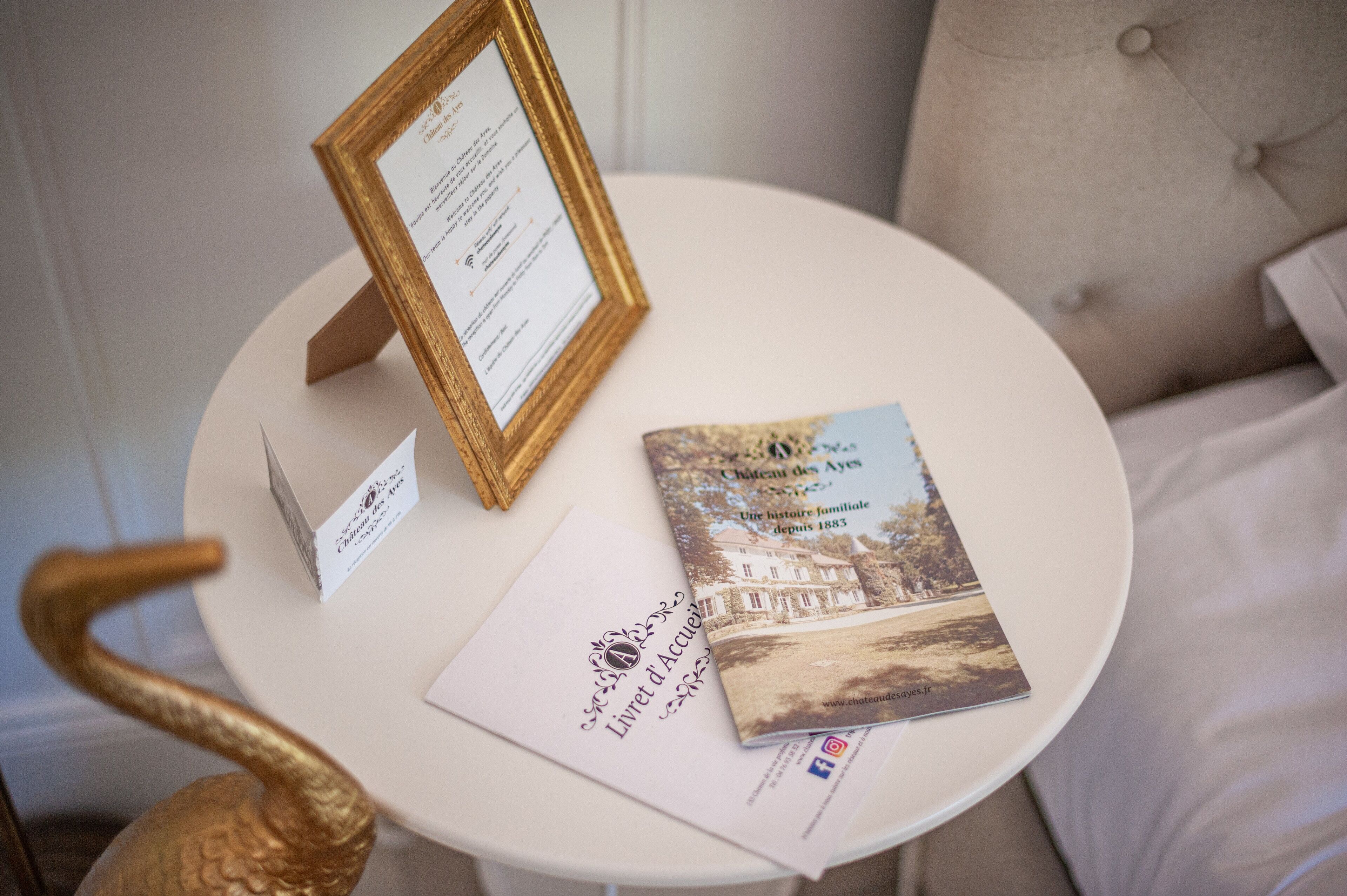 A round table with a framed welcome sign, a brochure, and a name tag.