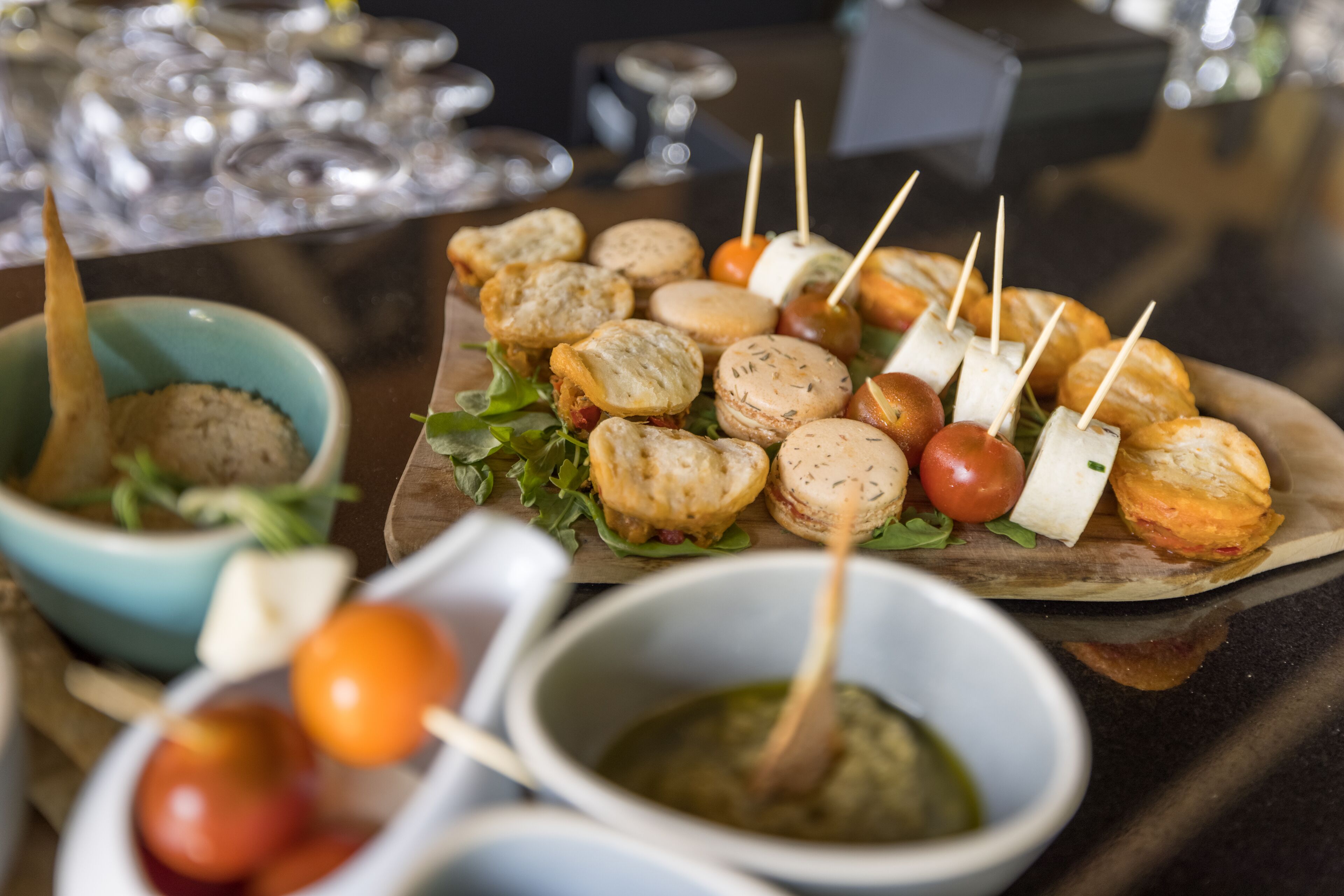 Diversos petiscos, incluindo pão, queijo e tomate, acompanhados de molhos para banhar e palitos.