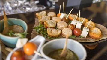 Diversos petiscos, incluindo pão, queijo e tomate, acompanhados de molhos para banhar e palitos.