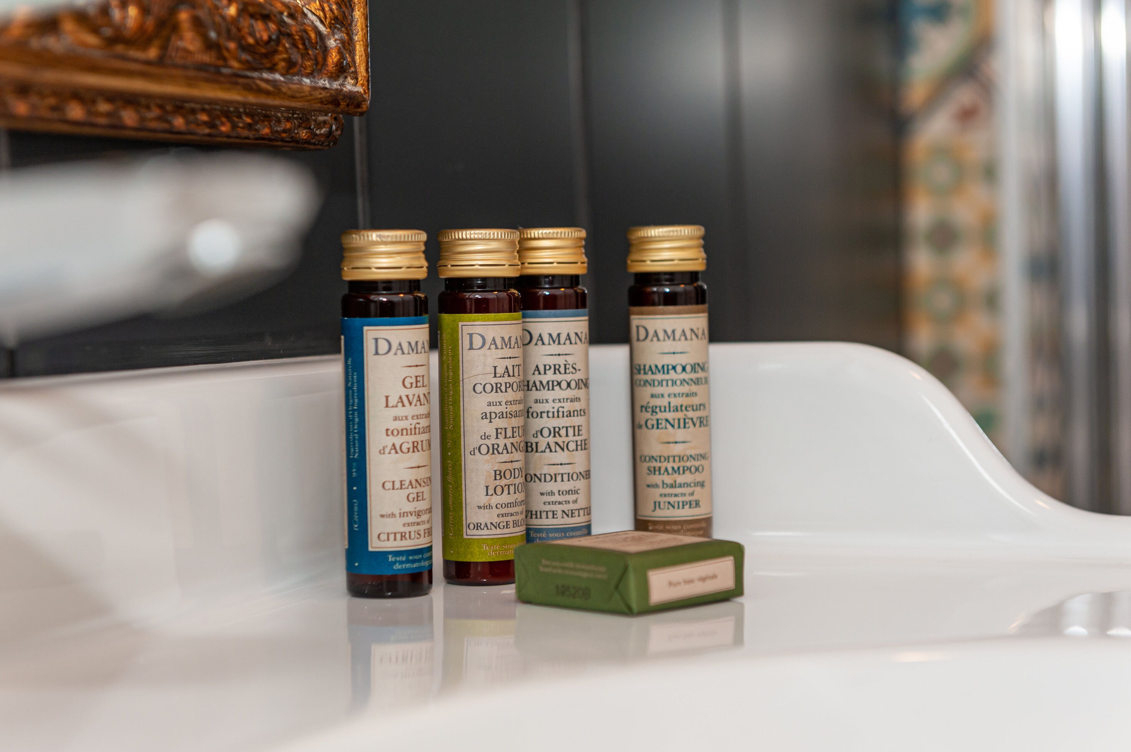 Un estante de baño con cuatro botellas de productos capilares Damana y una barra de jabón.