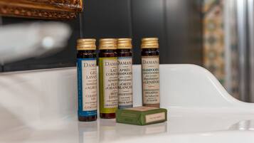 Un estante de baño con cuatro botellas de productos capilares Damana y una barra de jabón.