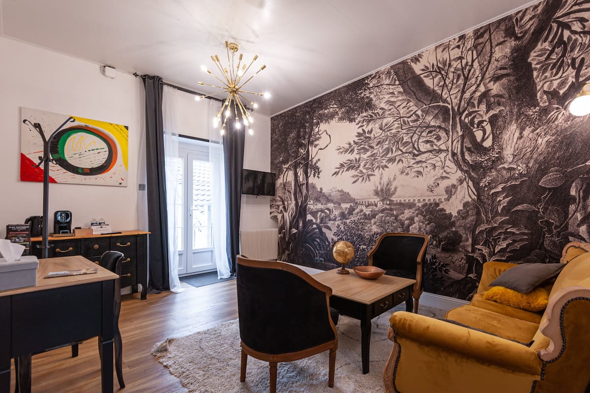 A modern living room with a dining area, a black and white mural, and a chandelier.