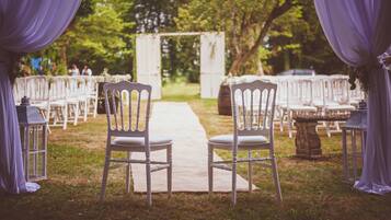 A wedding aisle with white chairs and a pathway.