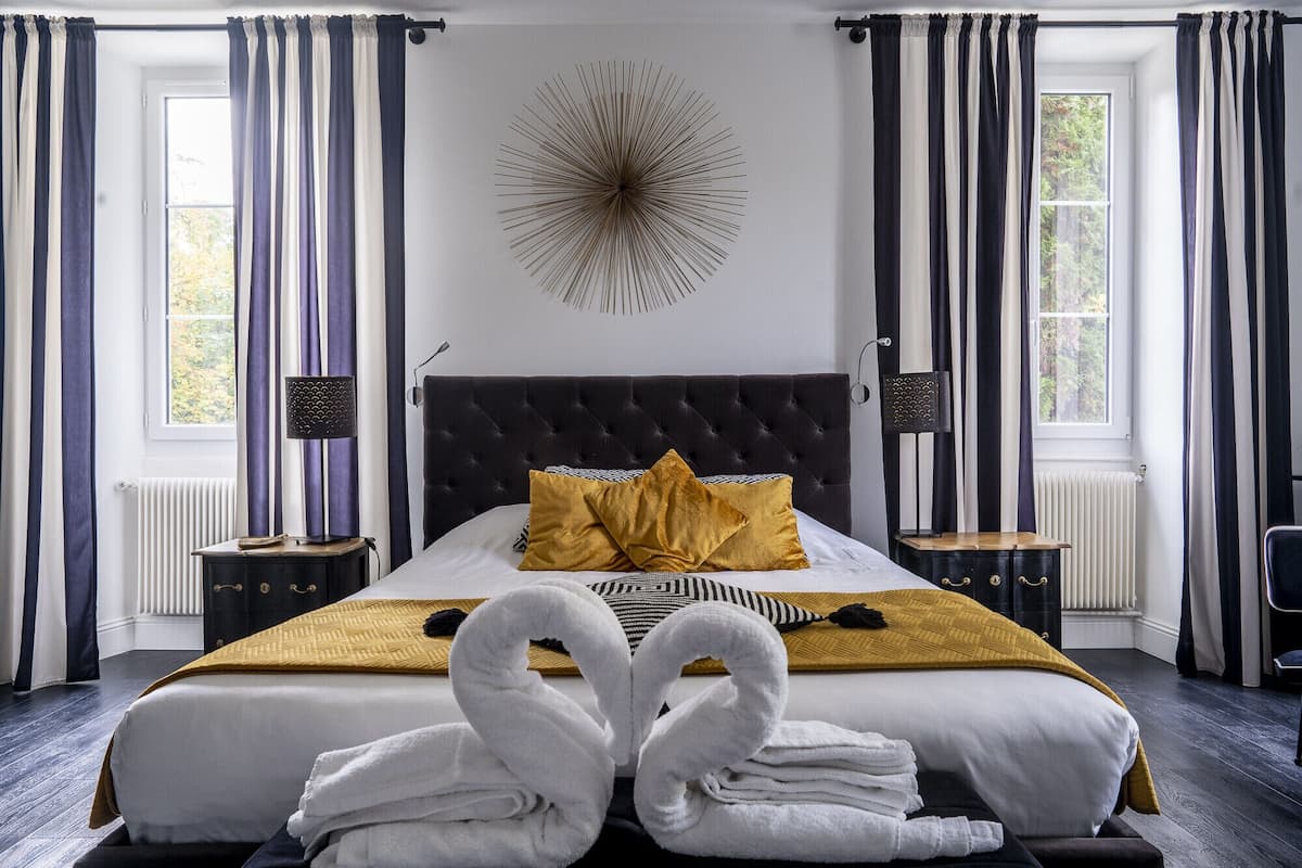 A bedroom with a large bed, two bedside tables, a wall-mounted lamp, and a decorative wall piece.