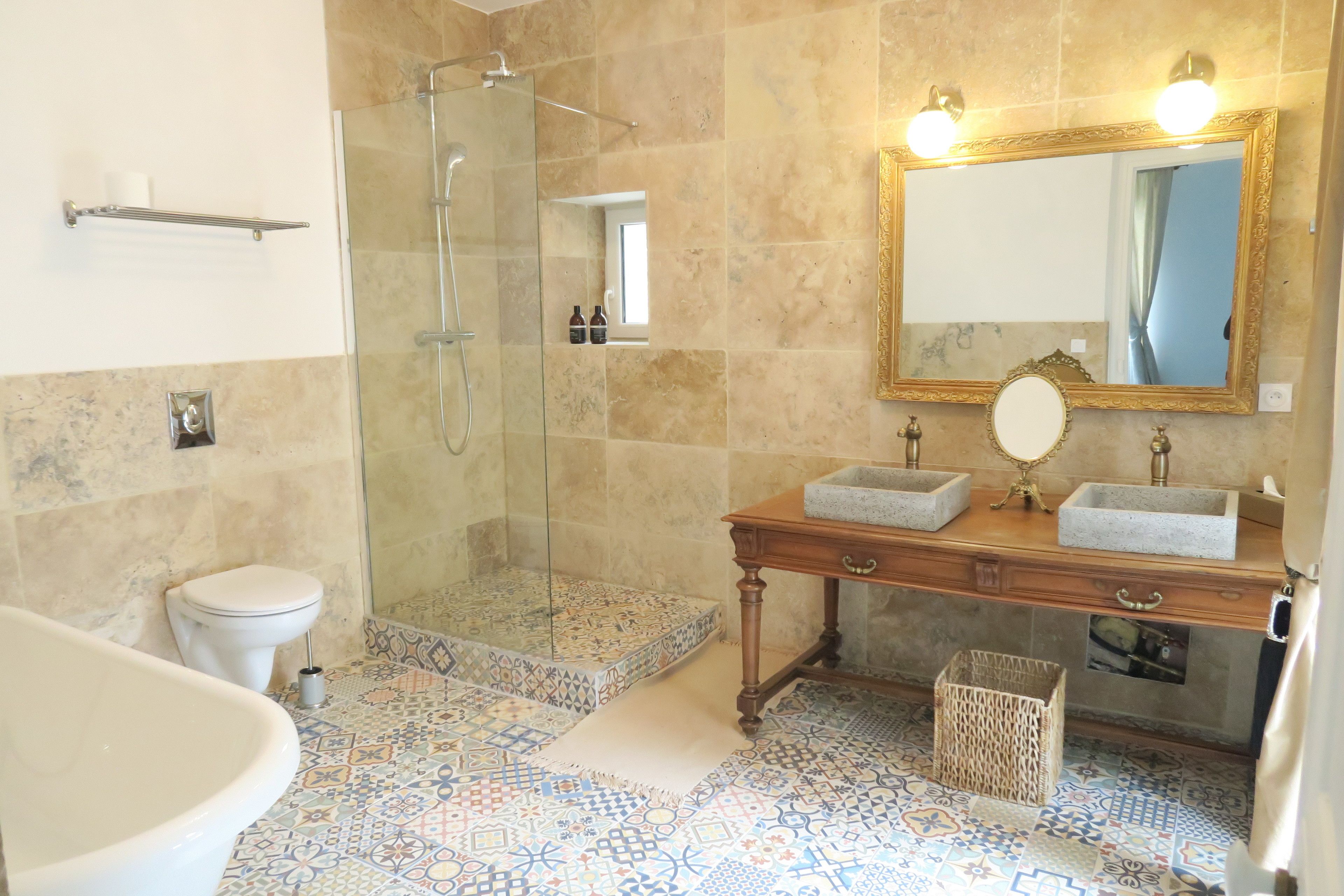 Un baño con ducha, inodoro, lavamanos y espejo con luces.