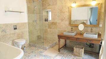 Un baño con ducha, inodoro, lavamanos y espejo con luces.