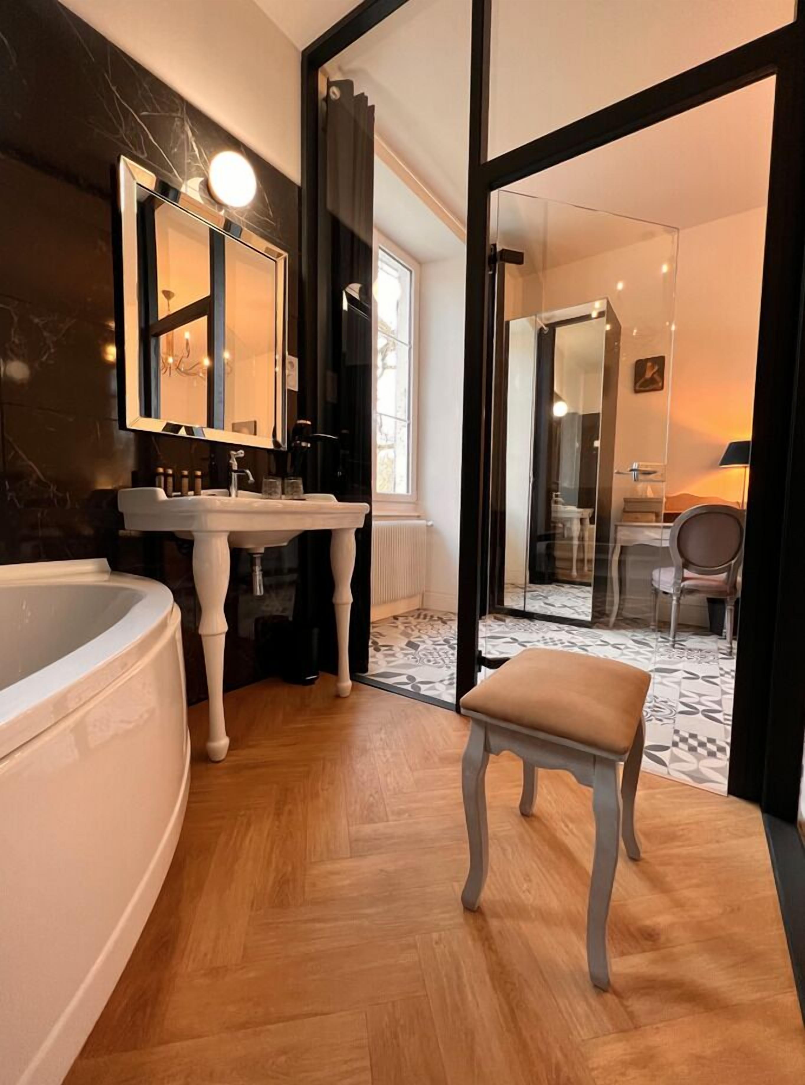 Une salle de bain moderne avec une grande baignoire, un meuble-lavabo avec un miroir et une chaise au premier plan.